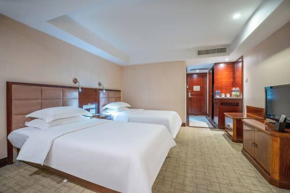Una habitación de hotel con dos camas, televisión, escritorio y armario.