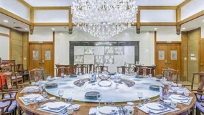 Un comedor formal con una mesa redonda dispuesta para una comida, rodeada de sillas de madera.
