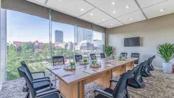 A conference room with a long table, chairs, a TV, and a city view.