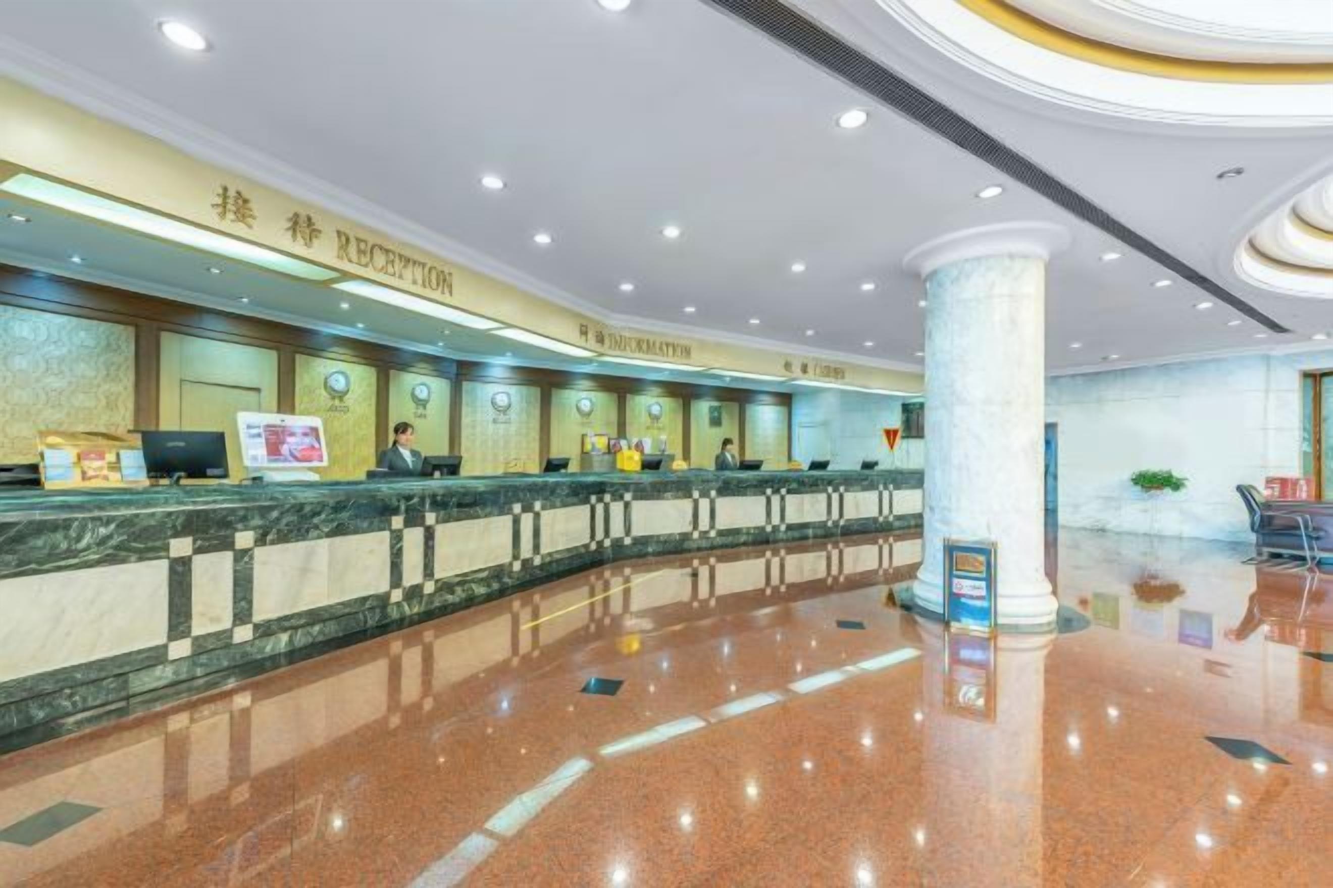 A hotel reception area with a marble counter, reception desk, and a large pillar.