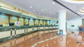 A hotel reception area with a marble counter, reception desk, and a large pillar.