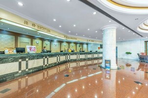 A hotel reception area with a marble counter, reception desk, and a large pillar.