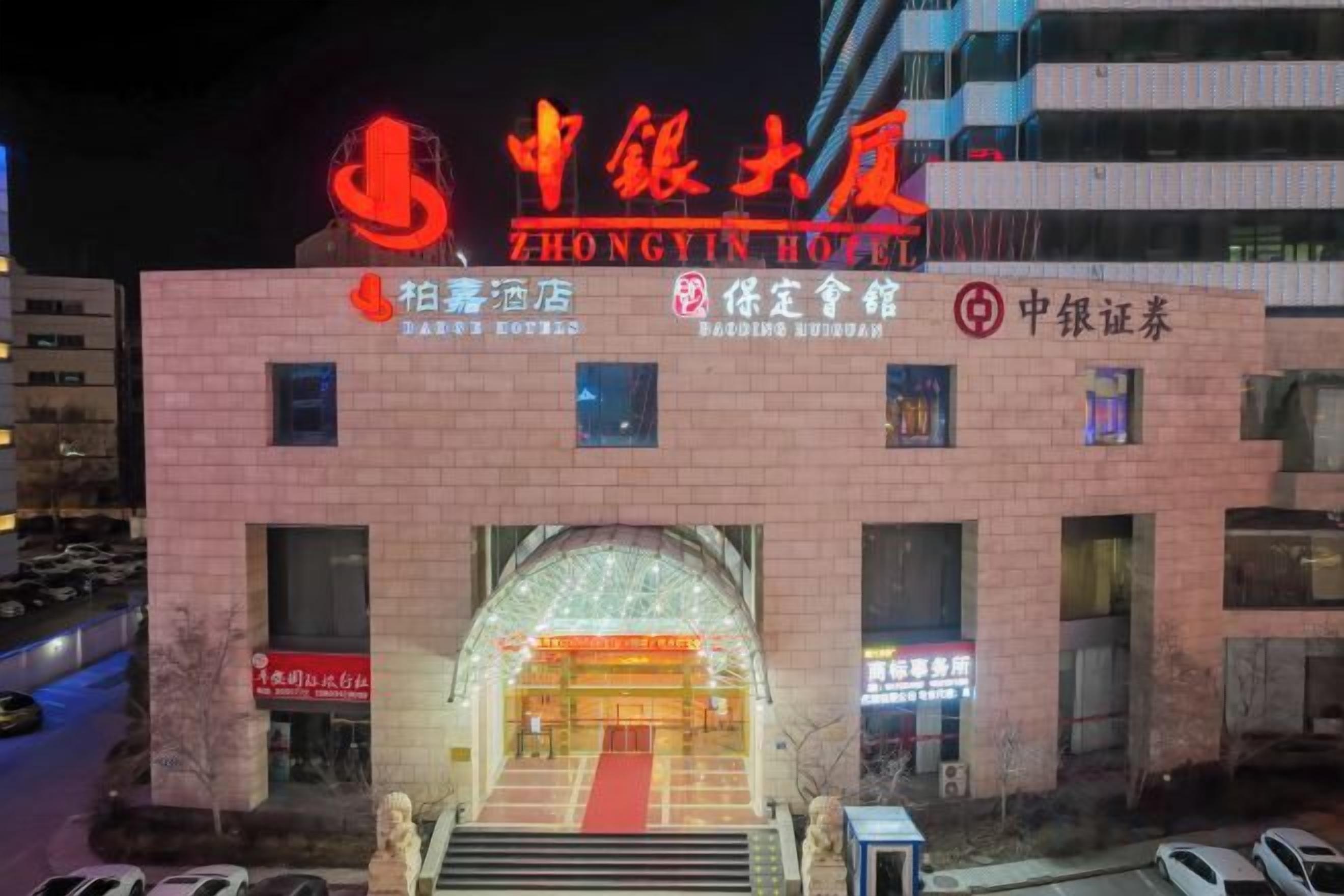 Un hotel con un cartel llamativo, múltiples ventanas y una entrada con alfombra roja.