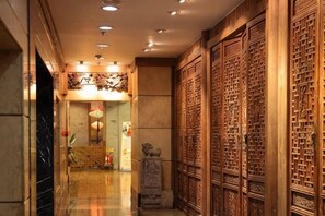 A corridor with wooden paneling, a stone sculpture, and a reception area with a decorative ceiling.