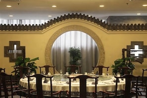 Un comedor con una mesa redonda, sillas y un ventanal con cortinas.