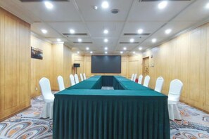 A conference room with a long table, white chairs, and a projector screen. - Zhongyin Hotel (Baoding)