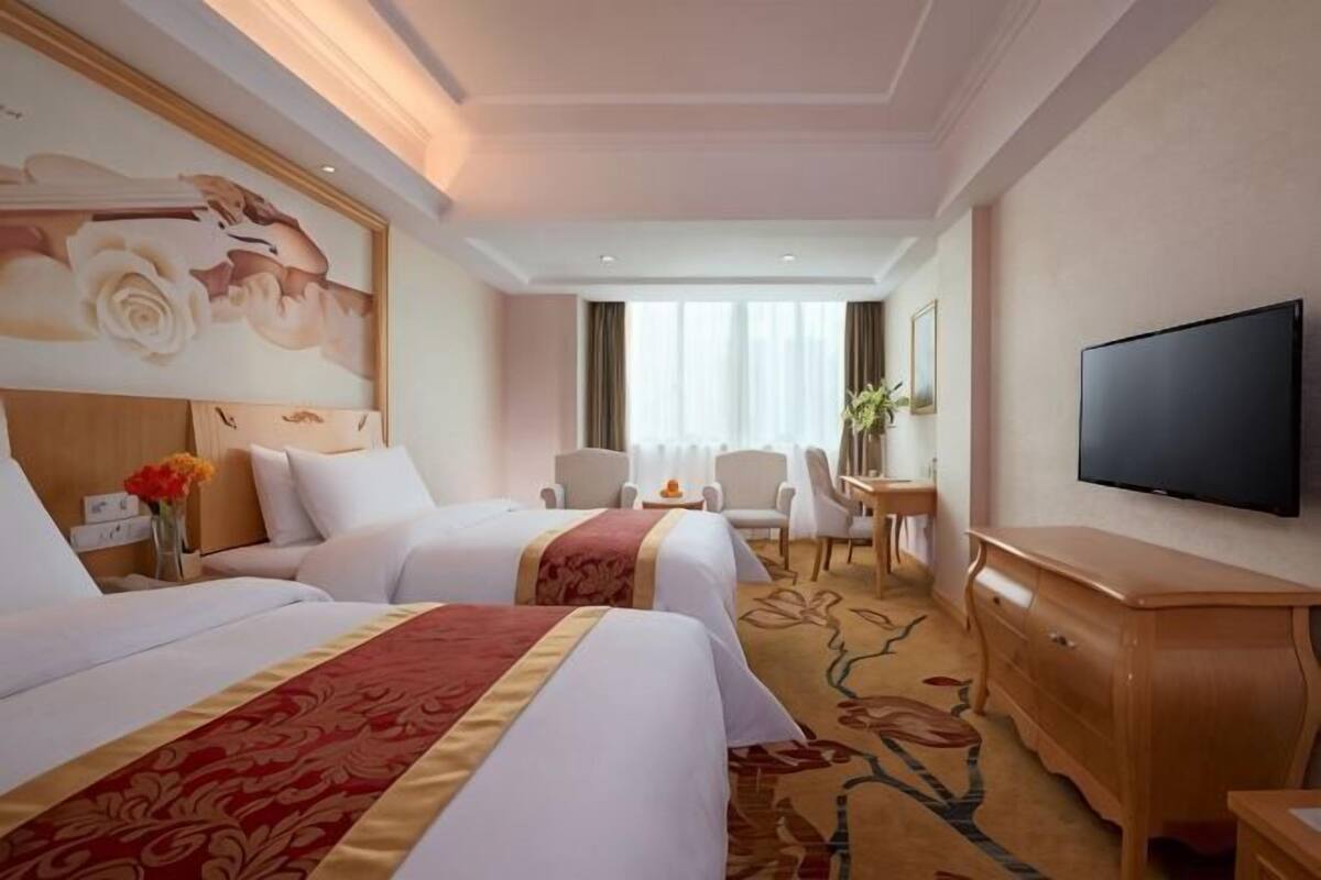 Ett hotellrum med två sängar, en TV, ett skrivbord och en stol.