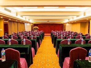 A conference room with rows of tables and chairs, a carpeted floor, and a stage at the front. - Vienna Hotel Lianjiang Road - Qingyuan (Qingyuan)
