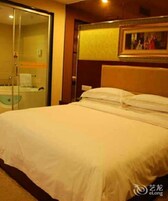 Una habitación de hotel con cama, cabina de ducha de vidrio y un cuadro en la pared.