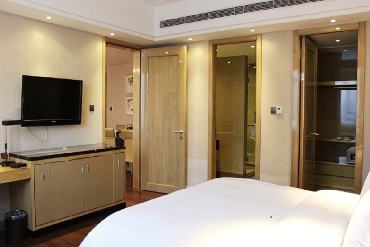 Una habitación de hotel con cama, televisión, escritorio y armario.