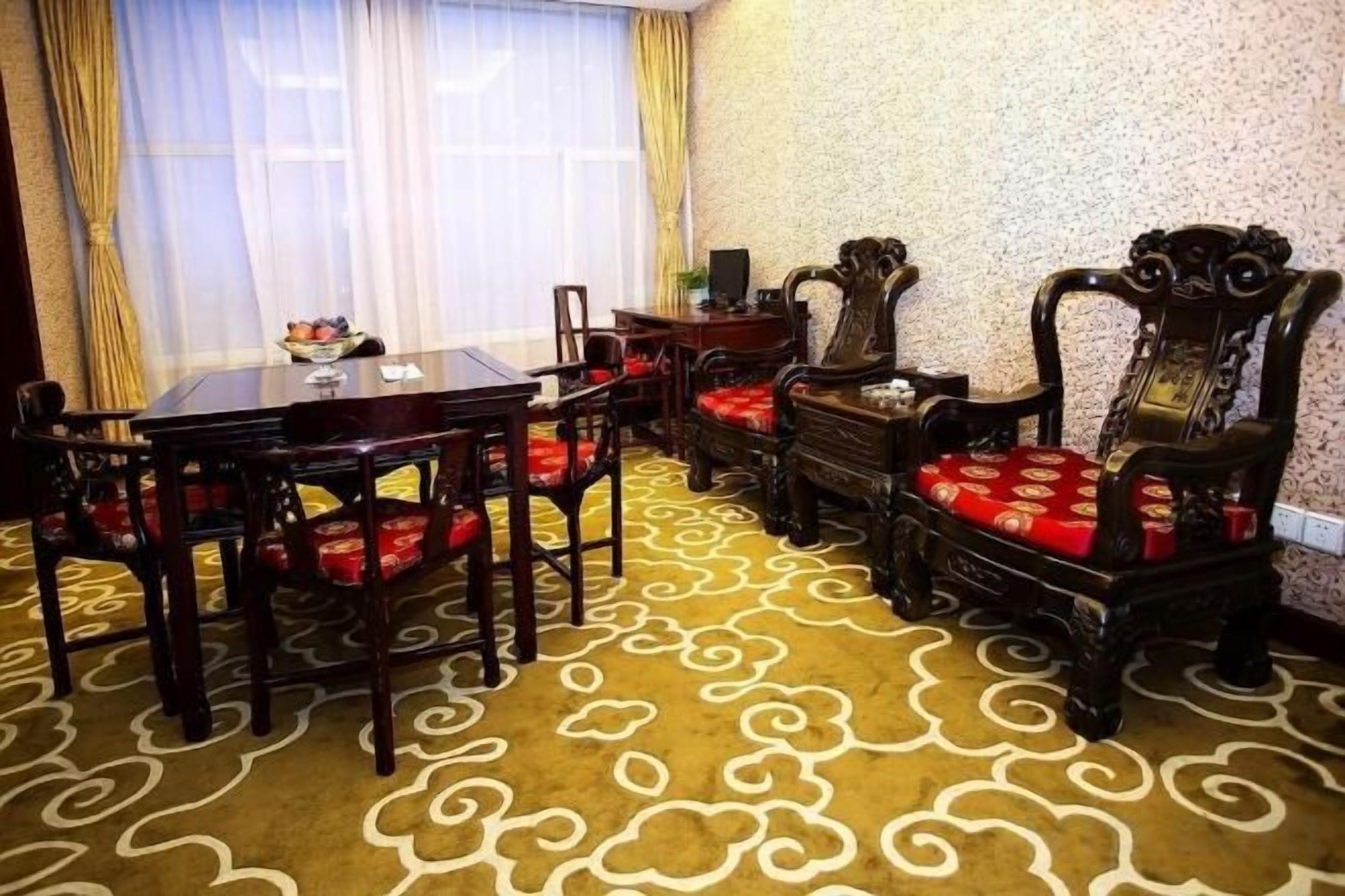 A dining area with a round table, chairs, and a patterned carpet.