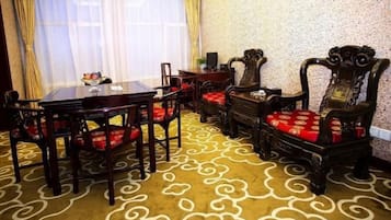 A dining area with a round table, chairs, and a patterned carpet.
