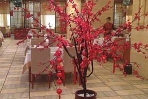 Un vestíbulo de hotel con una planta en maceta, mesas y sillas.