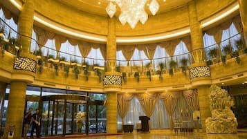A grand lobby with a circular layout, large columns, and a central chandelier.
