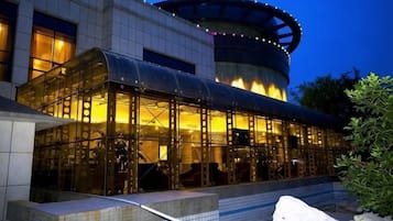 Un bâtiment moderne doté d’une façade en verre et d’une structure circulaire surmontée d’un toit.