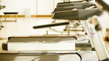 A treadmill in a gym with a mirrored wall and exercise equipment in the background.