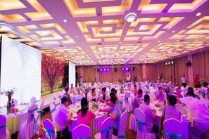 A banquet hall with round tables and chairs, a stage at the front, and a decorative ceiling. - Fengdu International Hotel (Weifang)