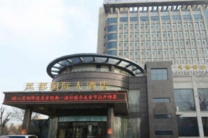 A hotel entrance with a modern design, featuring a curved glass facade and a prominent sign. - Fengdu International Hotel (Weifang)