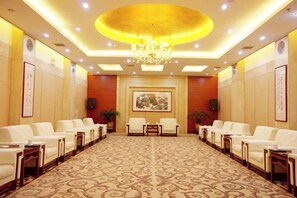 A conference room with a patterned carpet, rows of chairs, a chandelier, and framed artwork on the walls. - Fengdu International Hotel (Weifang)