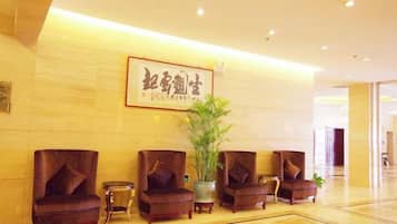 A reception area with a reception desk, four armchairs, a potted plant, and a framed sign on the wall.