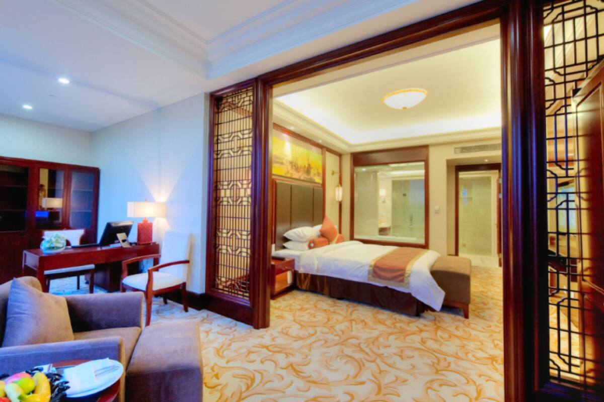Une chambre d’hôtel comprenant un lit, un bureau, une chaise, un canapé et un paravent décoratif.