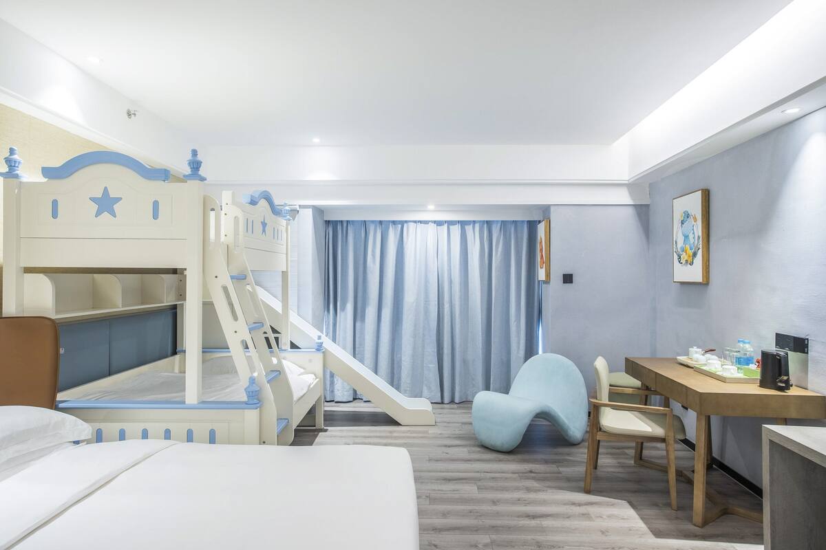 A child-friendly hotel room with bunk beds, a desk, and a chair.