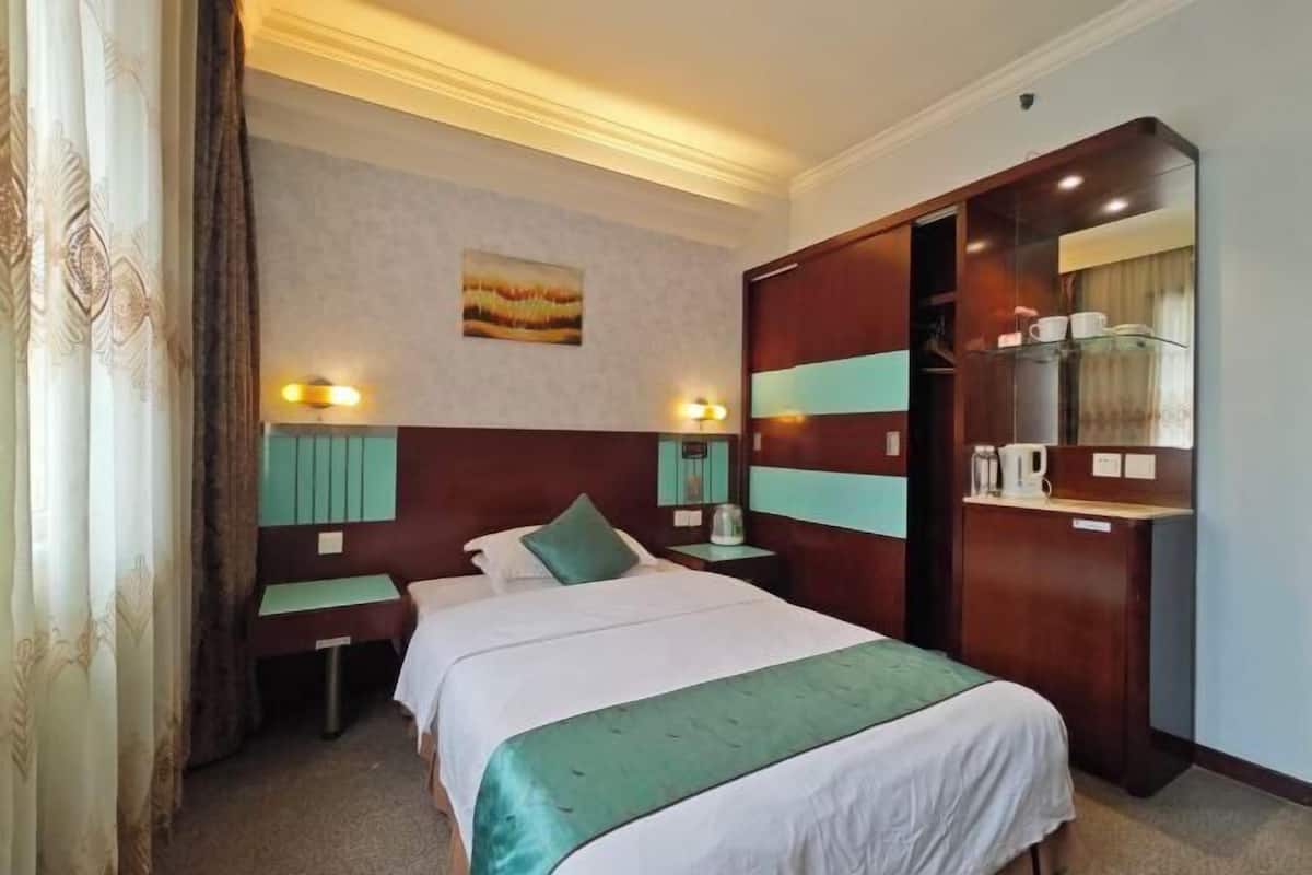 Een hotelkamer met een bed, nachtkastjes, een garderobe en een spiegel.