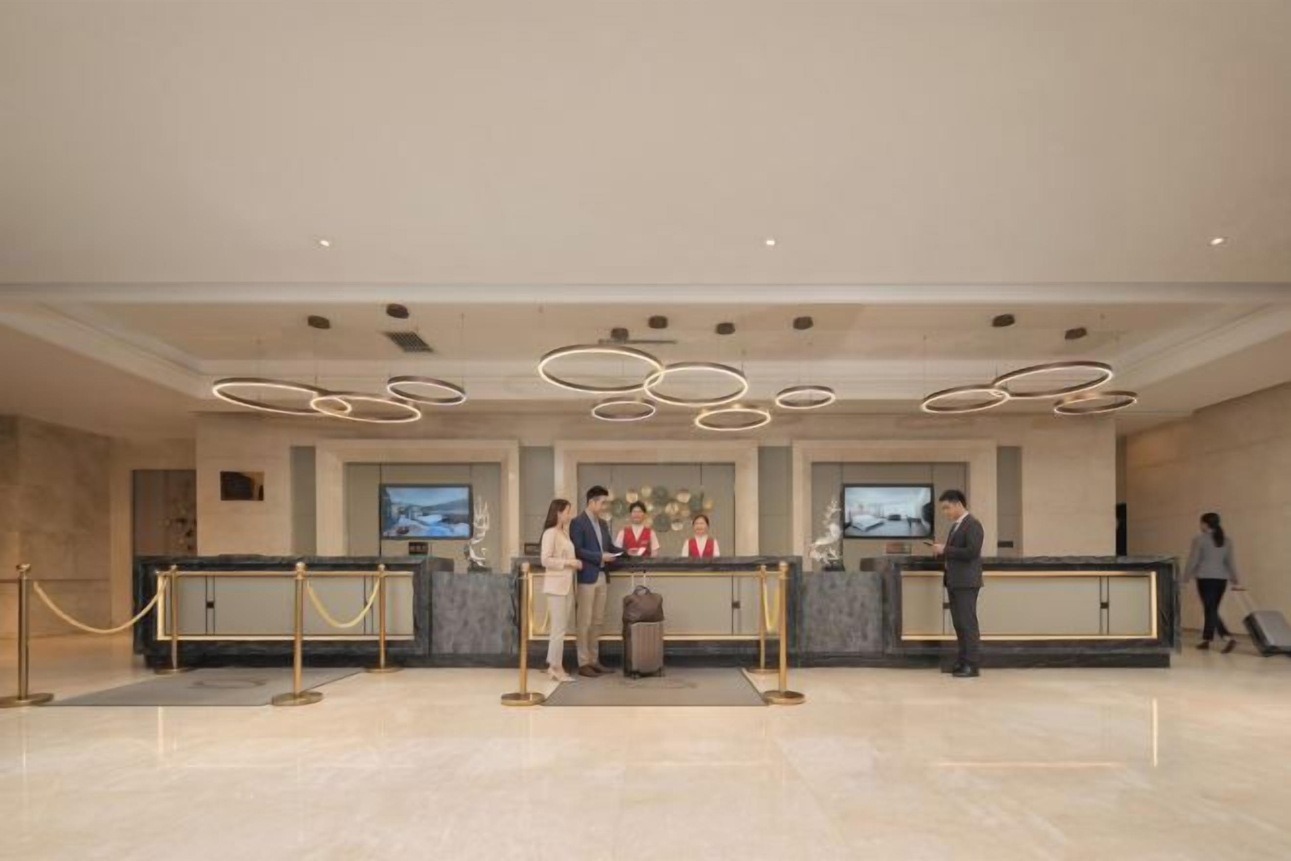 A hotel reception area with a modern design, featuring a reception desk, a trash bin, and a security barrier.