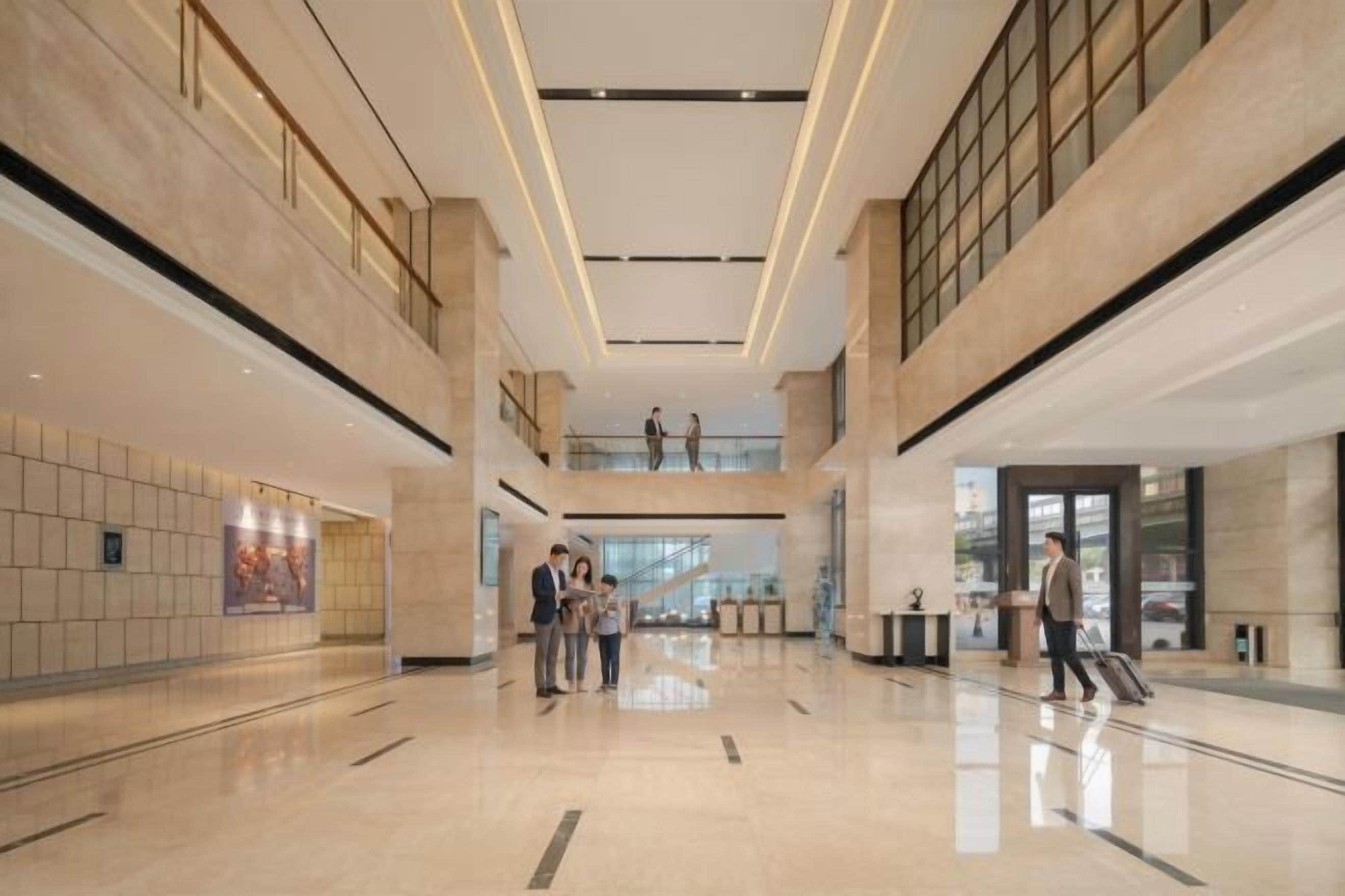Un hall d’entrée spacieux avec un plafond haut, des planchers polis et un escalier central.