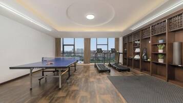 Une pièce équipée d’une table de ping-pong, de matériel d’exercice et d’une grande fenêtre donnant sur la ville.