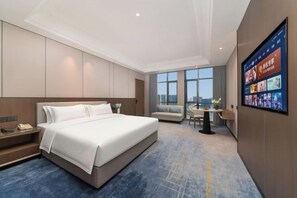 A modern hotel room with a large bed, a desk, and a view of the city. - Sylva Hotel (Changsha)