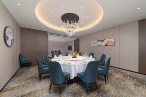 A conference room with a round table, blue chairs, and a chandelier. - Sylva Hotel (Changsha)