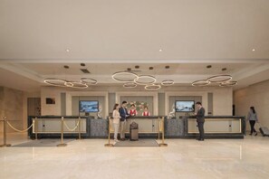 A hotel reception area with a modern design, featuring a reception desk, a television screen, and a seating area. - Sylva Hotel (Changsha)