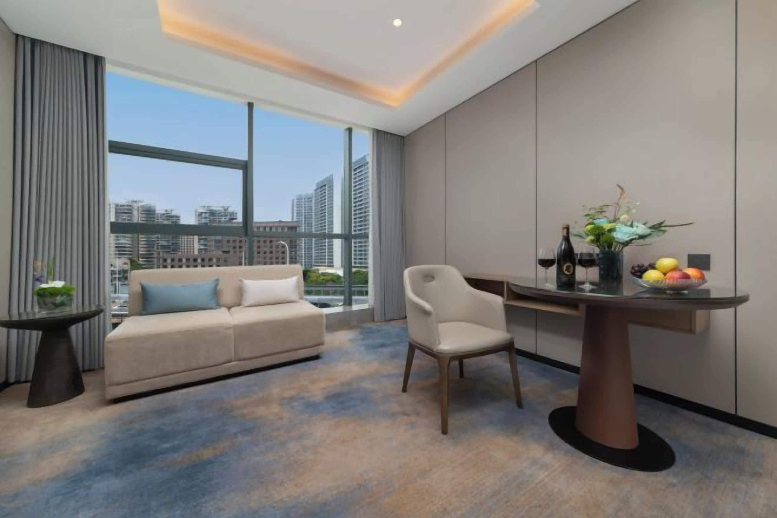 Une chambre d’hôtel moderne dotée d’une grande fenêtre, d’un canapé, d’une table à manger et d’une chaise.