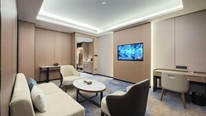A modern hotel room with a sofa, armchair, coffee table, TV, and a desk. - Sylva Hotel (Changsha)
