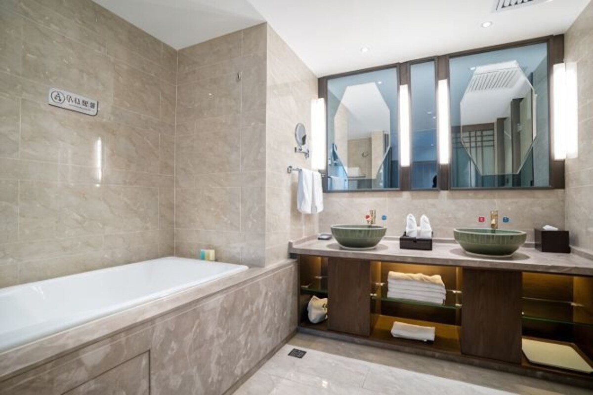 Un baño moderno con bañera, un espejo grande y un mueble de tocador con lavabo.