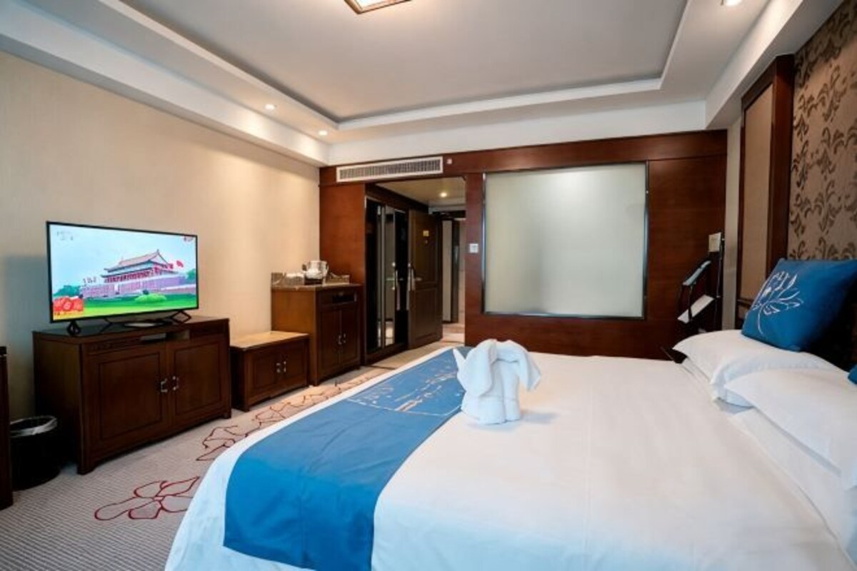 Una habitación de hotel con cama, televisión, escritorio y armario.