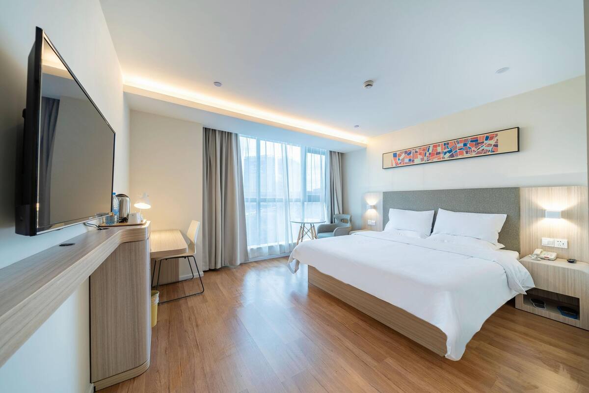 Une chambre d’hôtel moderne équipée d’un grand lit, d’un téléviseur à écran plat, d’un bureau et d’une chaise.