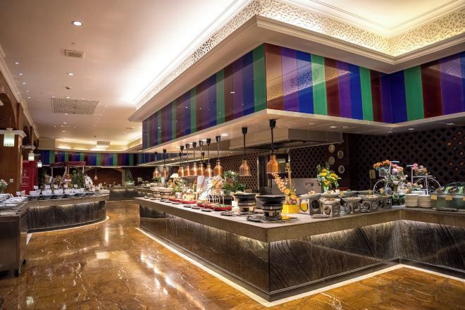A hotel lobby with a central bar area featuring a buffet setup.