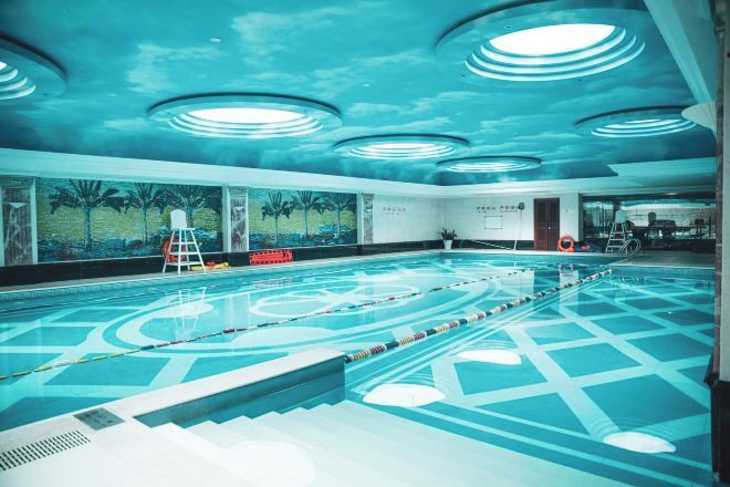A swimming pool with lane dividers, a lifeguard chair, and a mural on the wall.