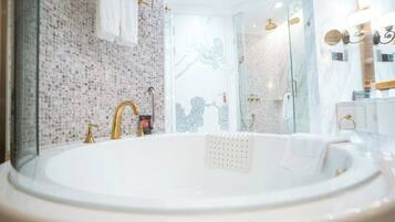 Un baño con una bañera grande, un grifo dorado y una pared de azulejos.