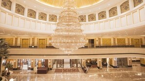 En rummelig lobby med en stor lysekrone, flere balkoner og en skinnende marmorgulv.