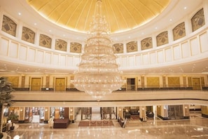 A spacious lobby with a large chandelier, multiple balconies, and a polished marble floor.