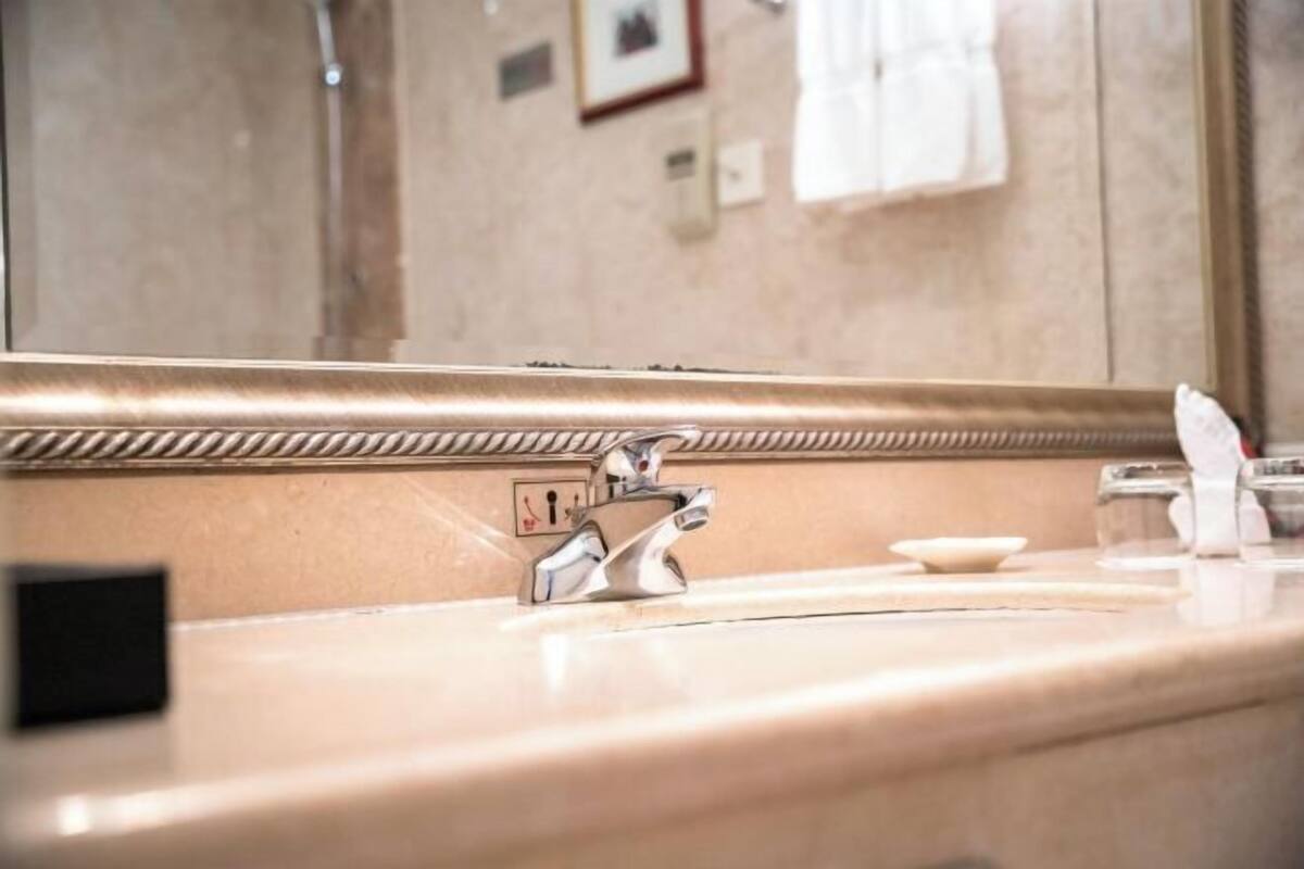 Une salle de bain avec un grand miroir, un lavabo et une serviette accrochée au mur.
