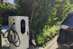 Una estación de carga para vehículos eléctricos con un coche estacionado cerca.