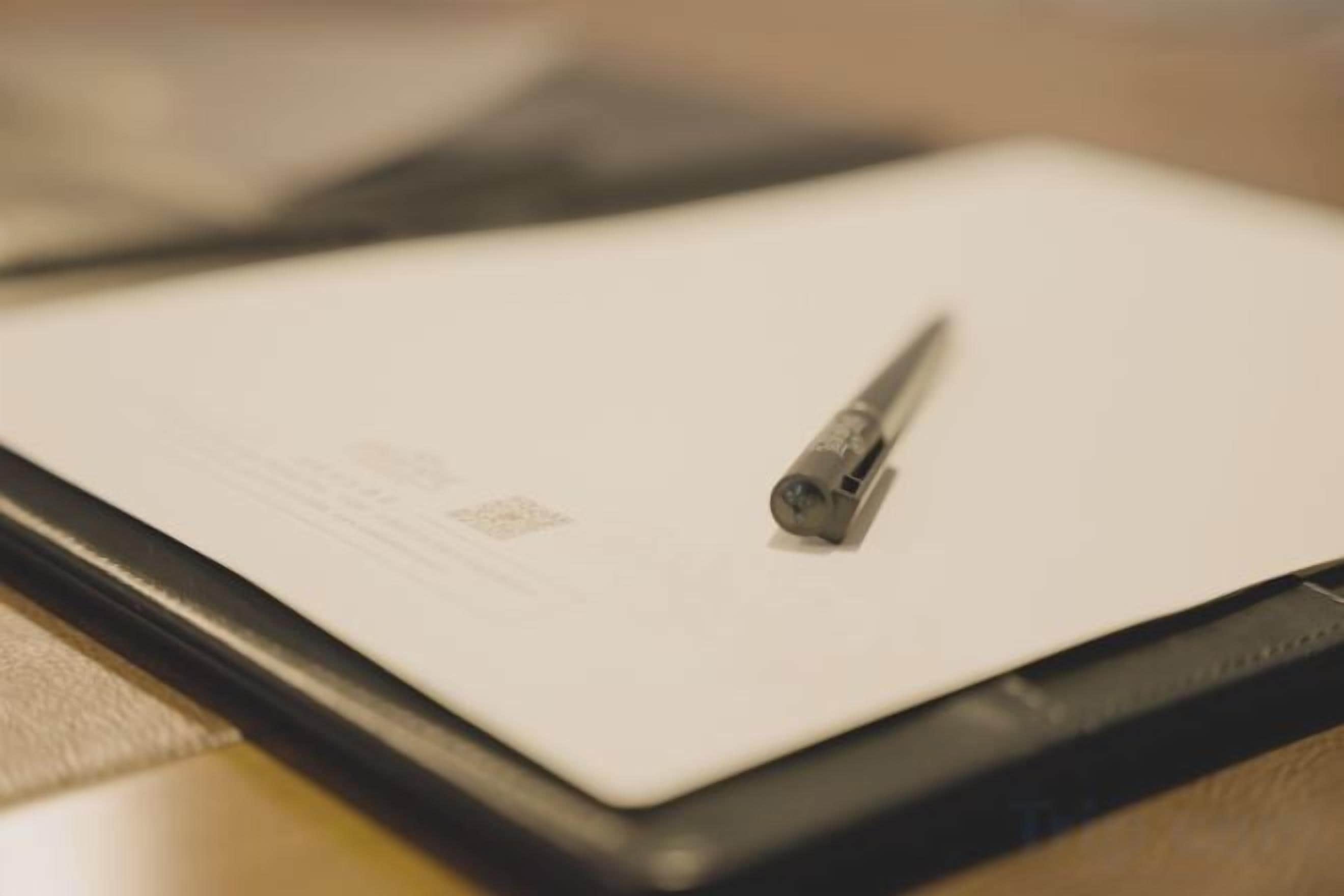 Um tablet com um stylus sobre uma superfície plana, possivelmente uma mesa ou escrivaninha.