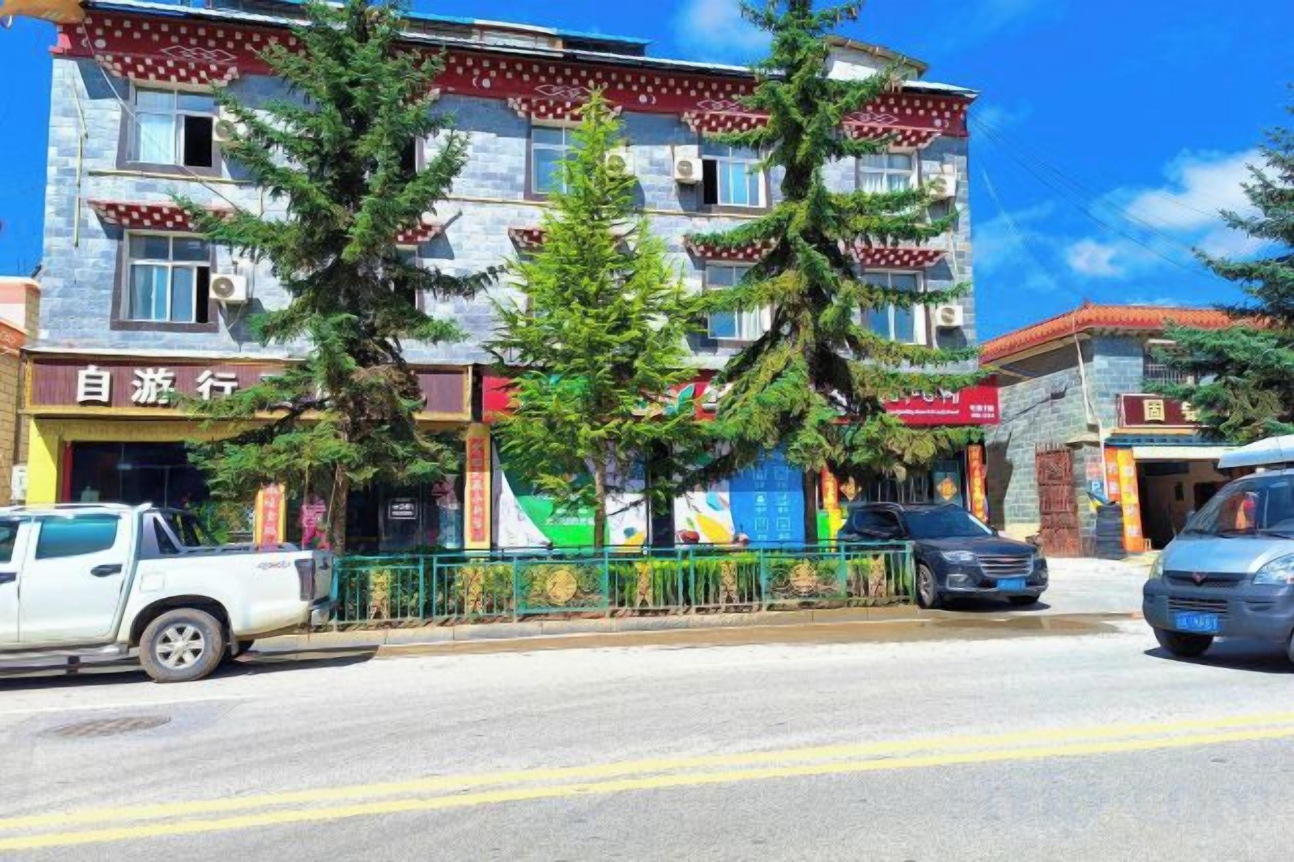 A multi-story building with a storefront on the ground floor, parked vehicles in front, and trees in front of the building.