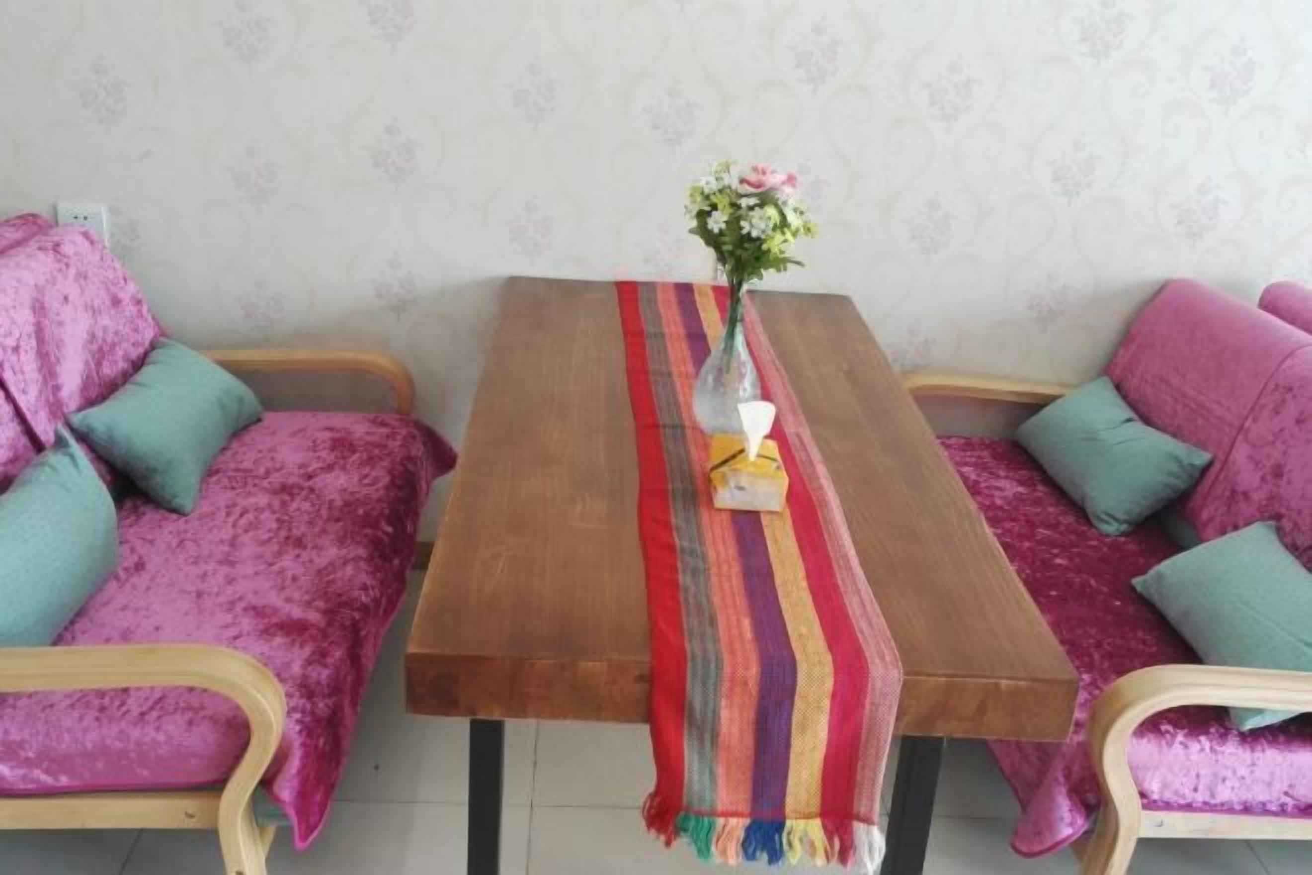 A room with a wooden table, two sofas, and a vase with flowers.