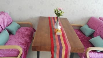 A room with a wooden table, two sofas, and a vase with flowers.