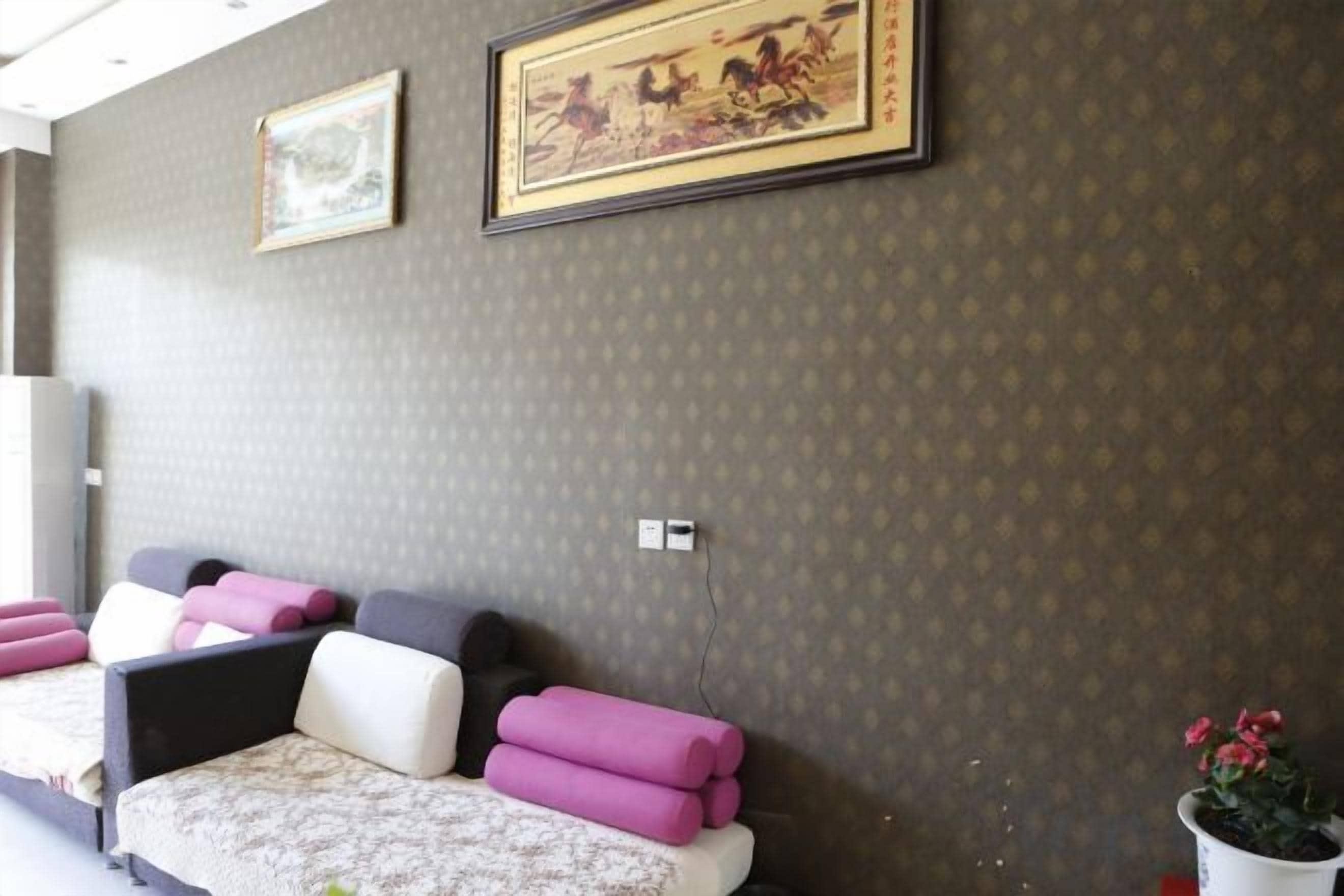 Uma área de espera com parede estampada, um sofá com almofadas e um quadro emoldurado.